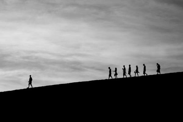 stock photo of a person walking down a hill away from a crowd