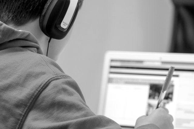 stock photo of a student with headphones on looking at a laptop